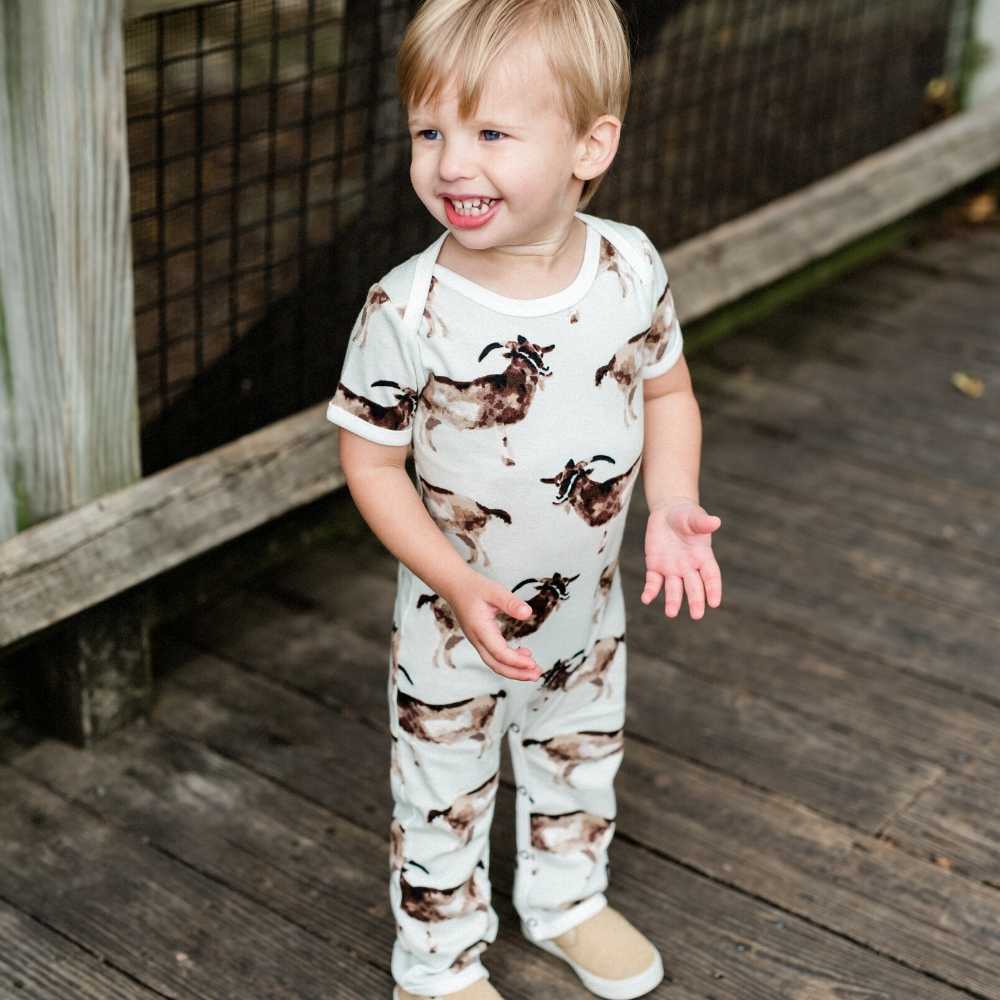 Little Baby Boy on a Bridge Wearing an Organic Romper or Jumpsuit in the Goat Print by Milkbarn Kids