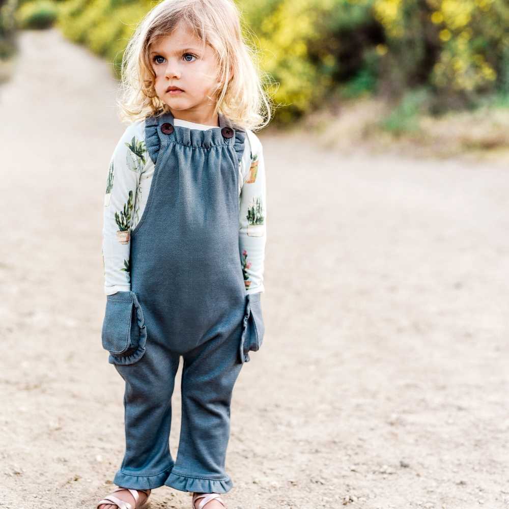 Little Girl on a Dirt Path wearing Milkbarn Kids Ruffle Overall in the Denim and Organic Fabric