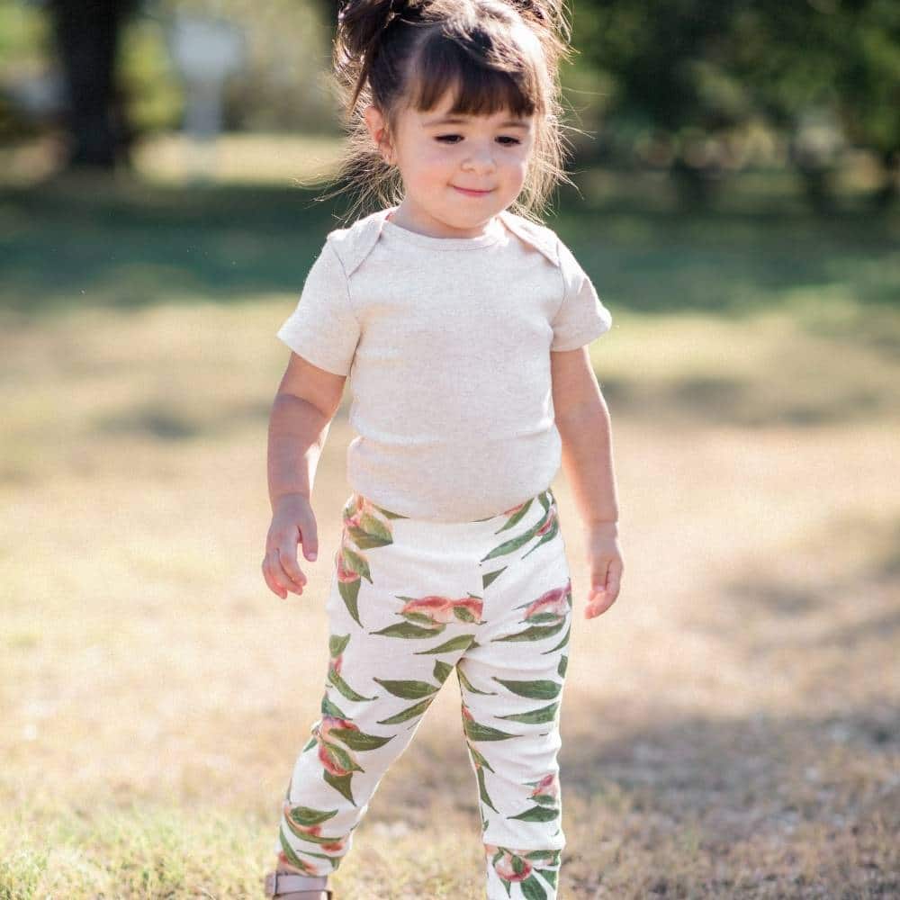 Baby Girl in a Field Wearing the Peaches Organic Cotton Leggings by Milkbarn Kids