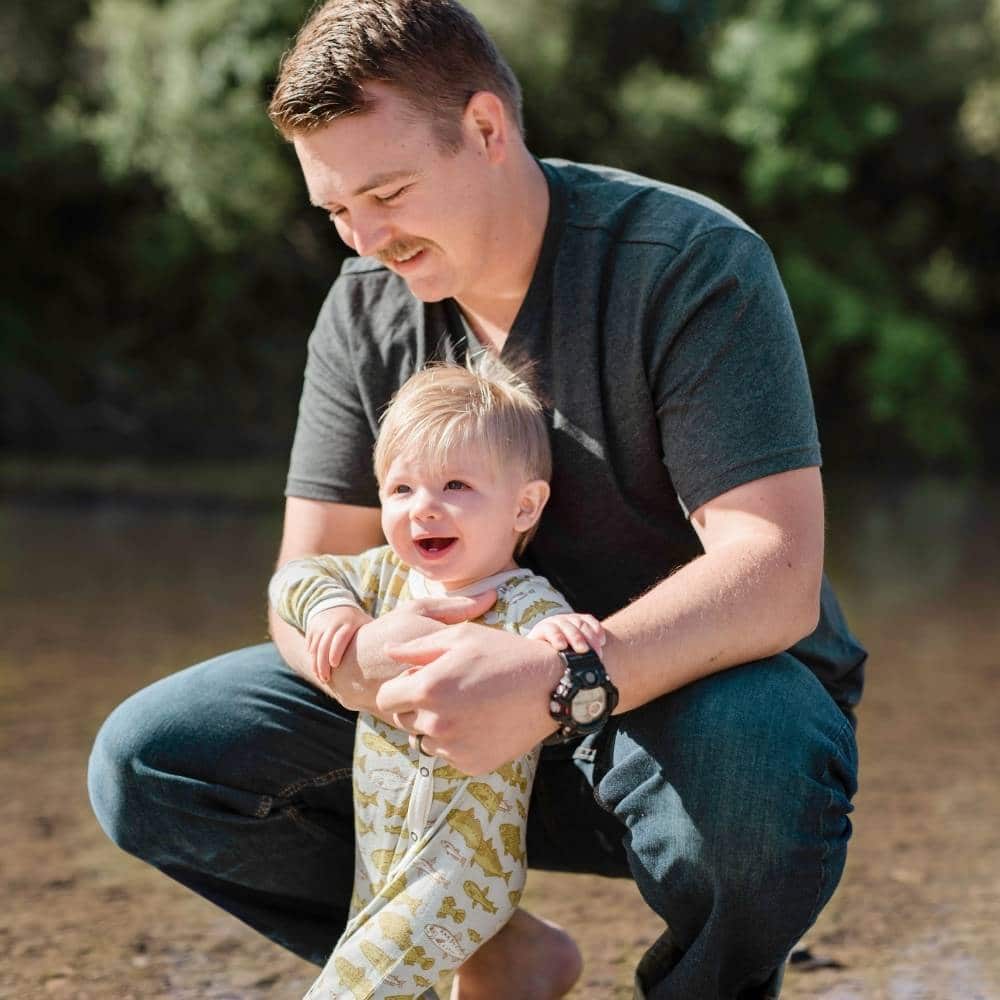 Dad and Son by the Water Wearing the Bamboo Blue Fish Footed Romper by Milkbarn Kids