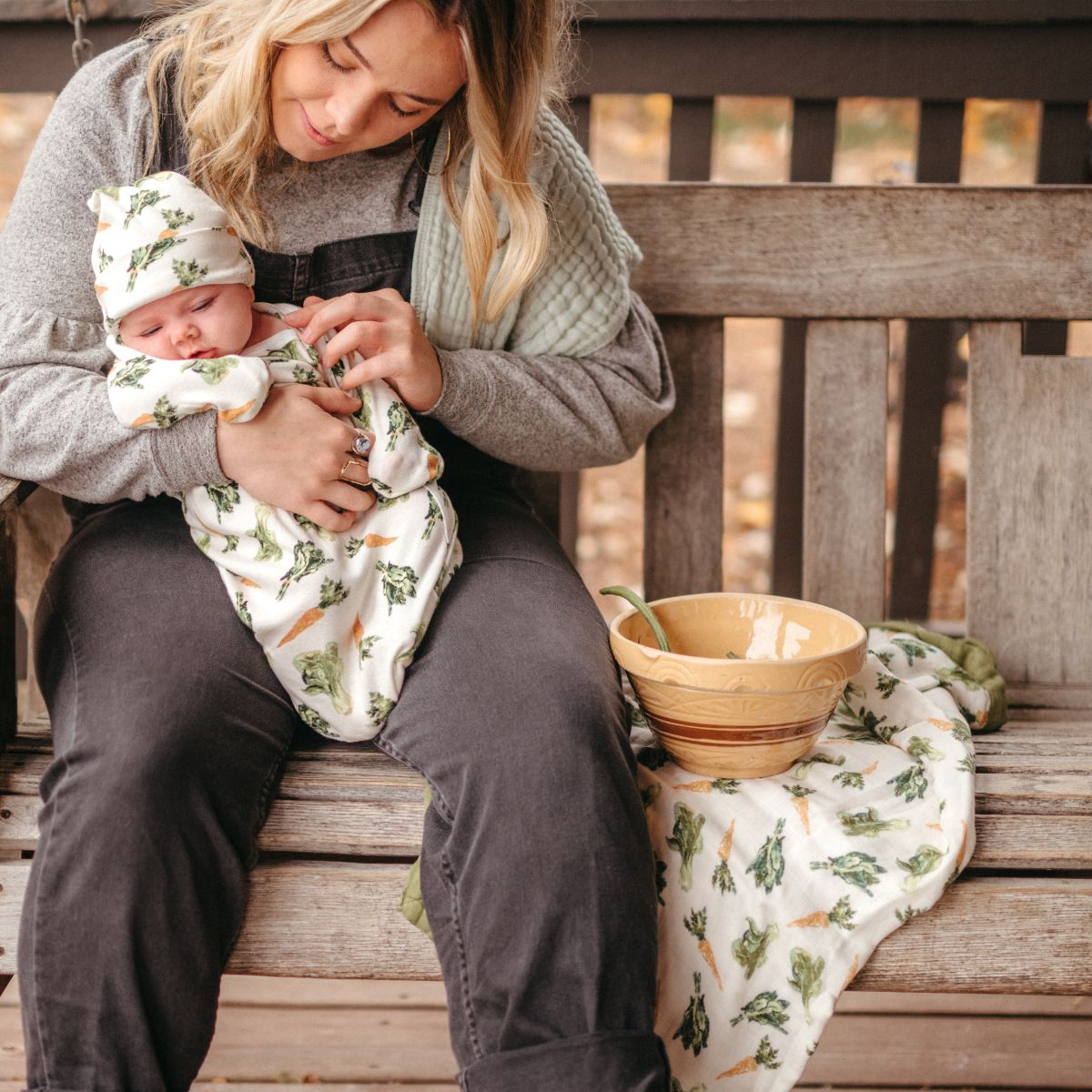 Mom and newborn baby with the Big Lovey blanket in the Fresh Veggies print and the baby in the newborn gown and hat set with the Fresh Veggies Print by Milkbarn Kids