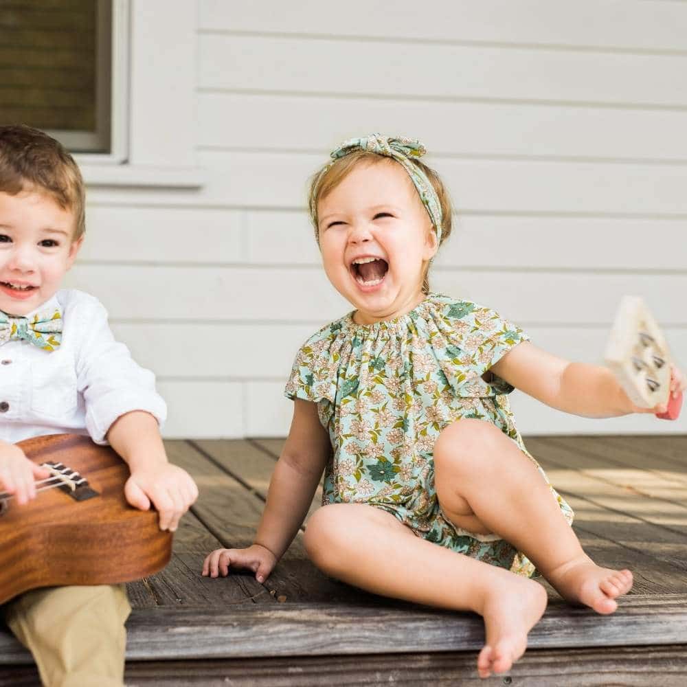 Baby Boy and Girl on a Porch Wearing the Blue Floral Bamboo Dress and Bloomers by Milkbarn Kids