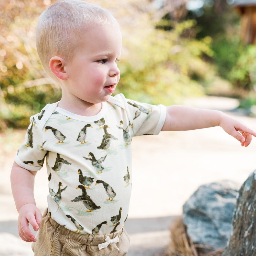 Baby boy outside pointing to a rock wearing the Duck Organic Cotton One Piece by Milkbarn Kids