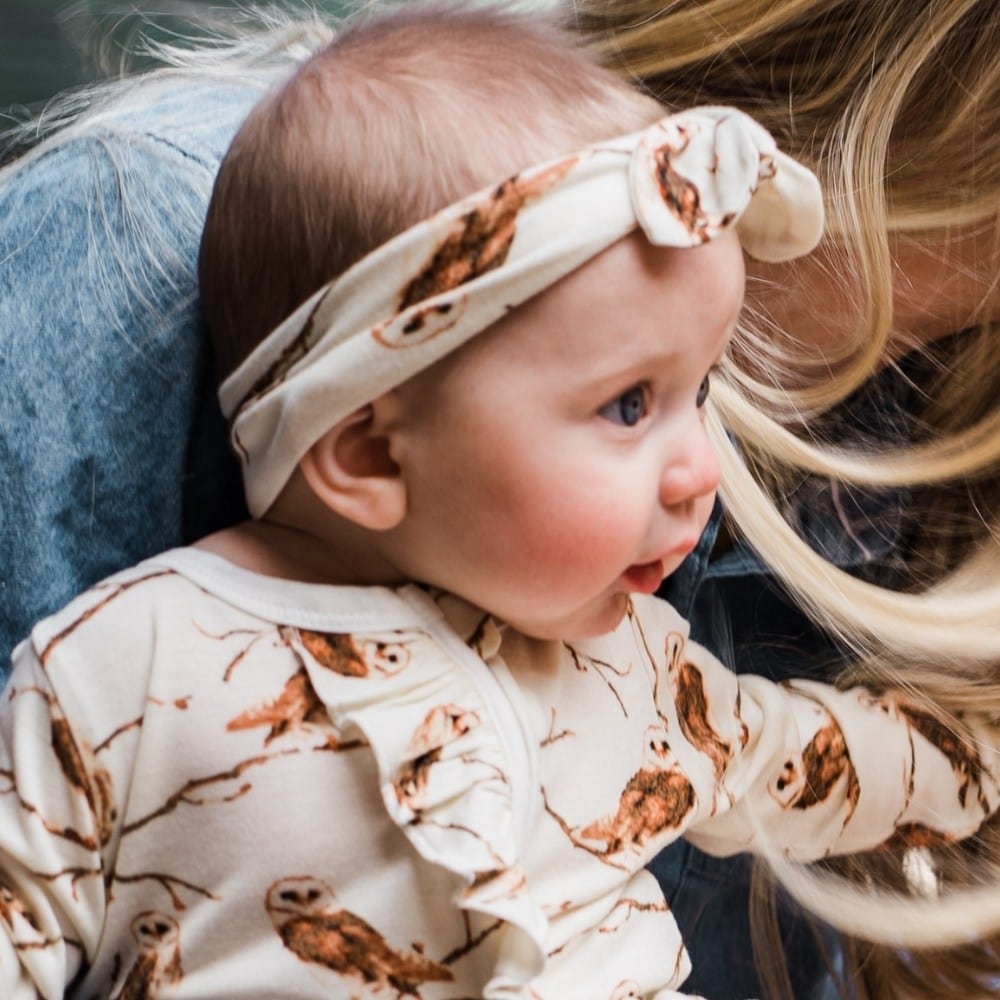 Baby girl on a Mom's lap wearing the Knotted Headband in the Owl print by Milkbarn Kids