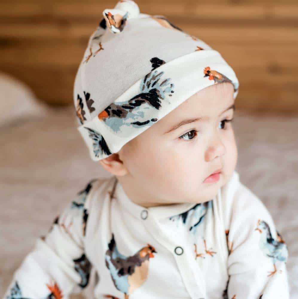Little Baby Wearing the Organic Cotton Knotted Hat or Beanie in the Chicken and Rooster Print by Milkbarn Kids