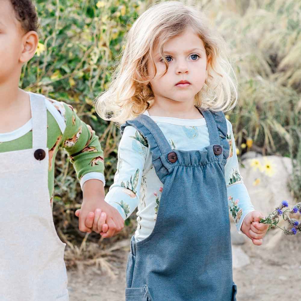 Little Boy and Girl holding hands in Milkbarn Kids Organic Ruffle Overall in Denim