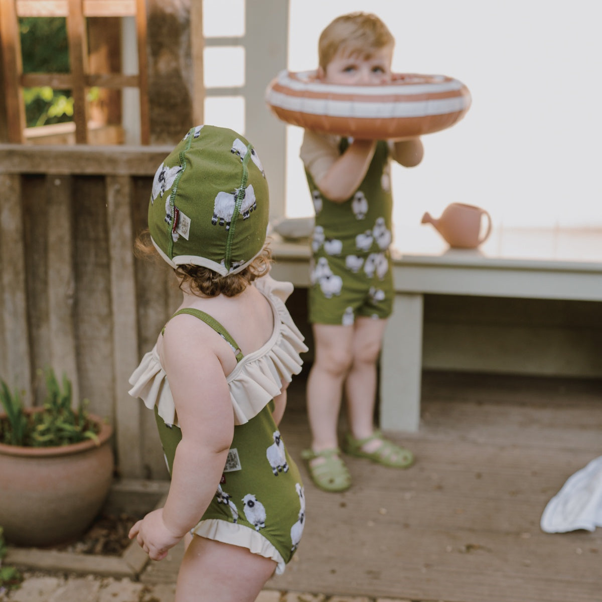 baby boy and girl outside near the pool wearing the Milkbarn swimwear collection in the Valais Sheep Print