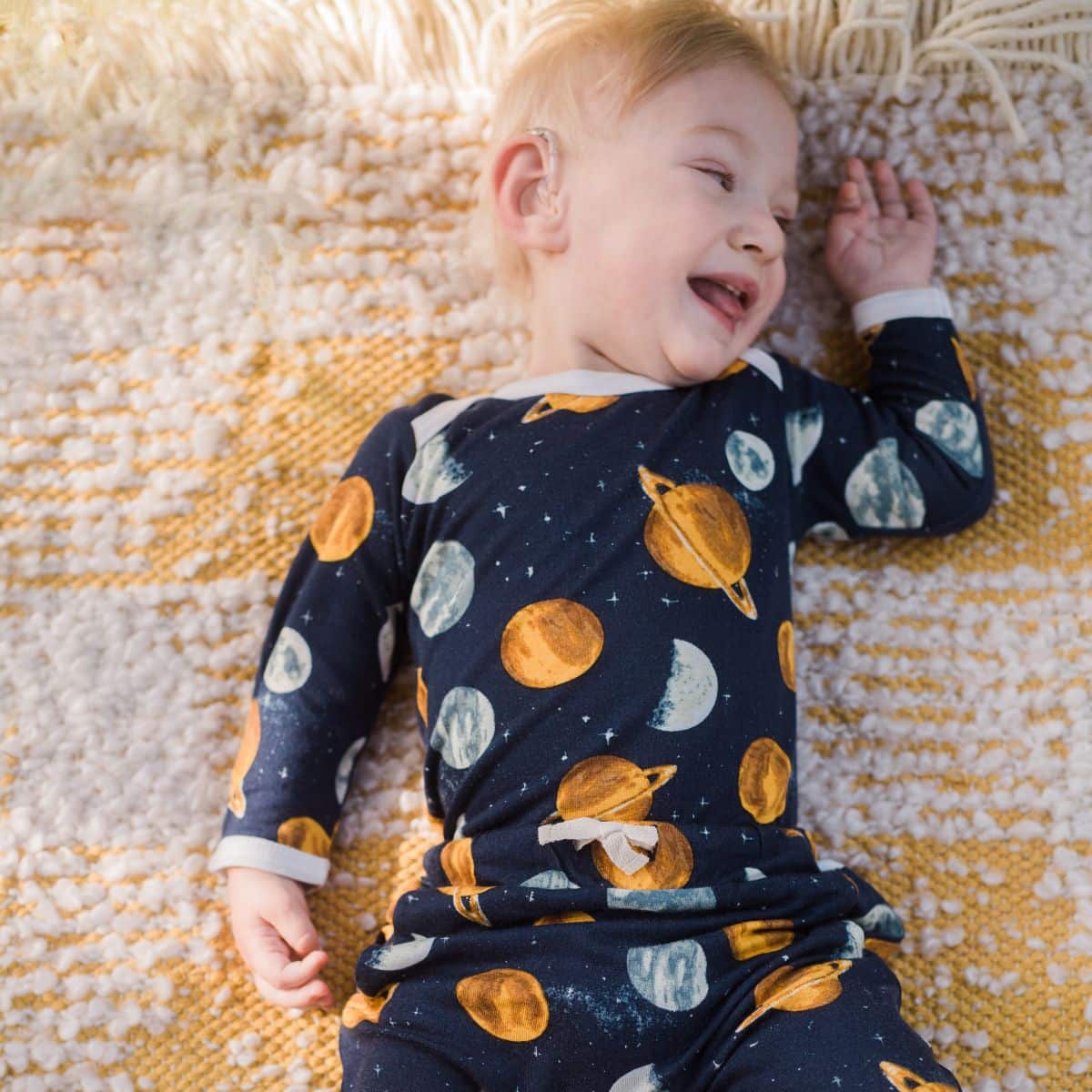 Baby boy laying down wearing the Planets Bamboo Jogger Pants and Long Sleeve One Piece by Milkbarn