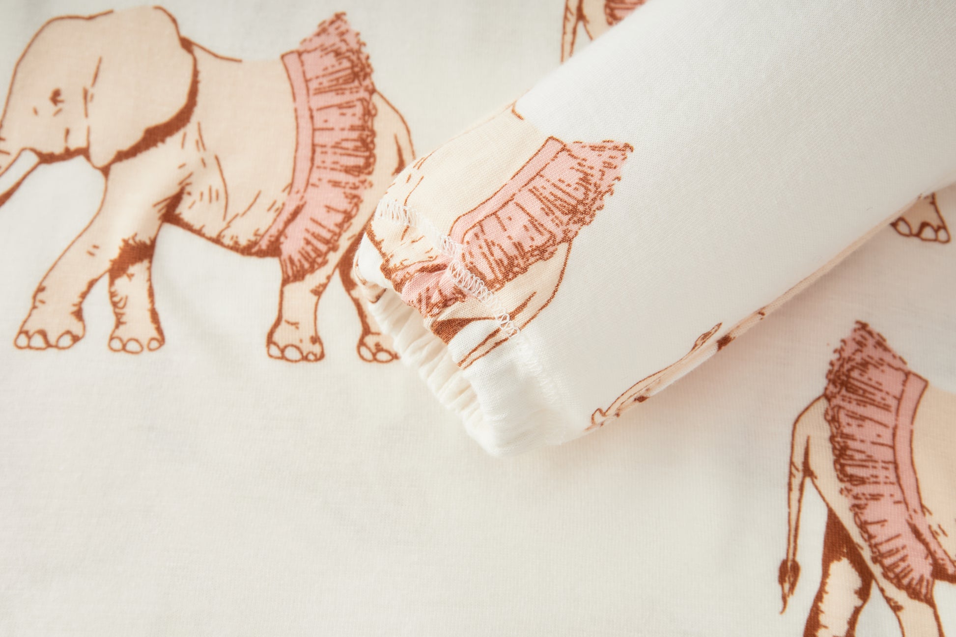 Close-up detail of Tutu Elephant bamboo fabric and sleeve on Milkbarn baby girl dress and legging outfit set, white with pink elephants in tutus