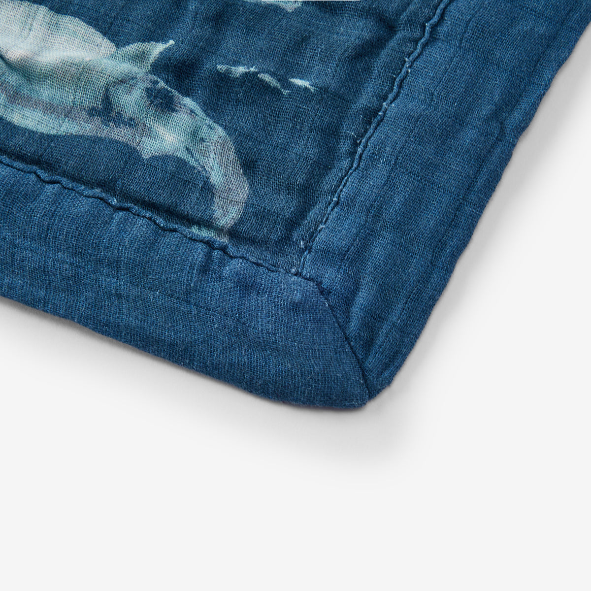 Close-up view of Blue Whale Big Lovey blanket showing dark blue trim and precise stitching detail