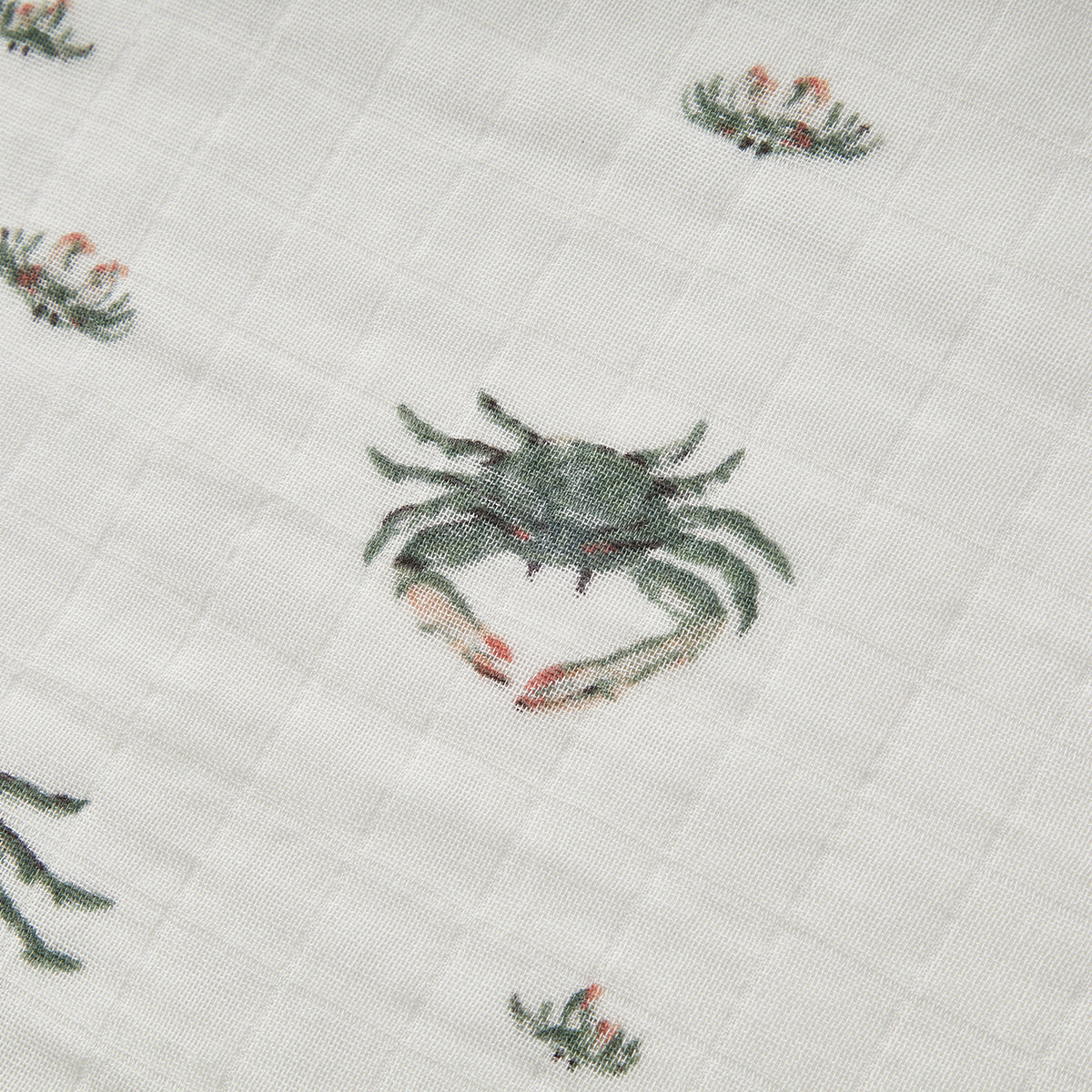 Closeup of Milkbarn Coastal Crab Bamboo Muslin Swaddle Blanket, showing soft breathable 70% rayon bamboo and 30% cotton fabric with playful green and blue crab print for newborns