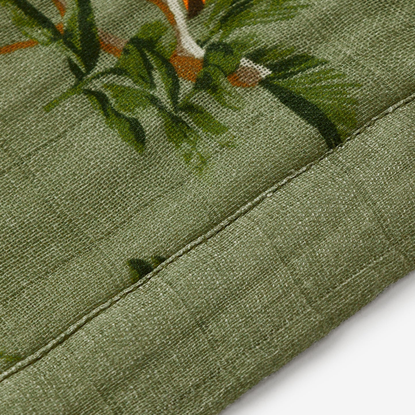 Closeup of Toucan Bamboo Mini Lovey muslin fabric and dark green trim for boys and girls