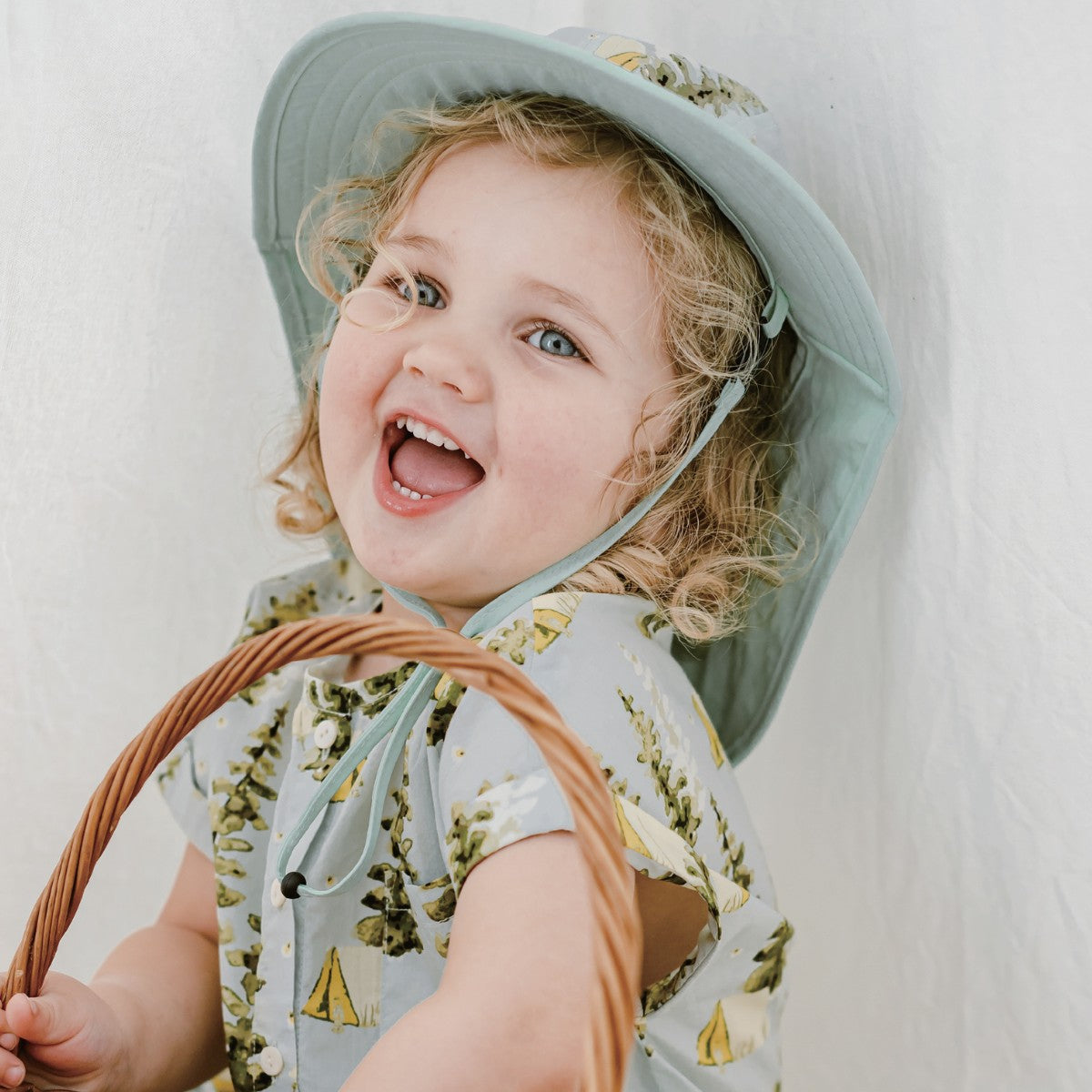 Toddler girl smiling while wearing the Camping Sun Safety Adjustable Hat
