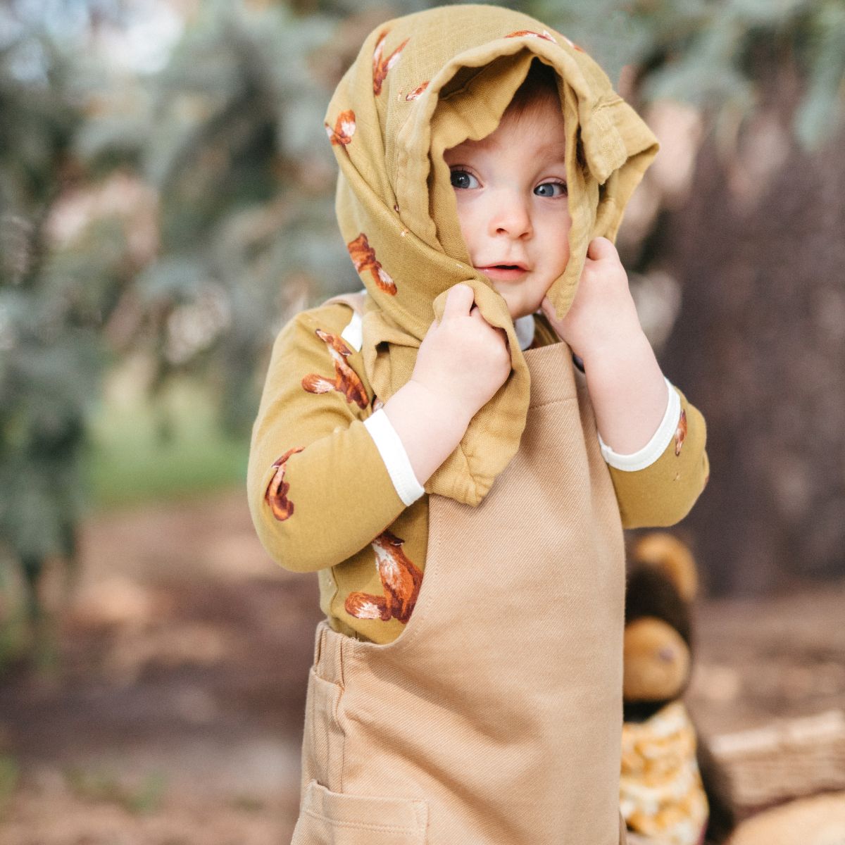 Toddler boy playing and wrapping Milkbarn Gold Fox Mini Lovey muslin security blanket around his head