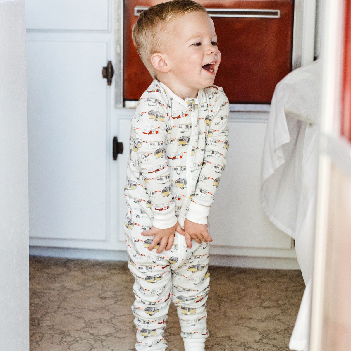 Baby Boy in a vintage trailer wearing the organic zipper pajamas with the vintage trailers print by Milkbarn Kids