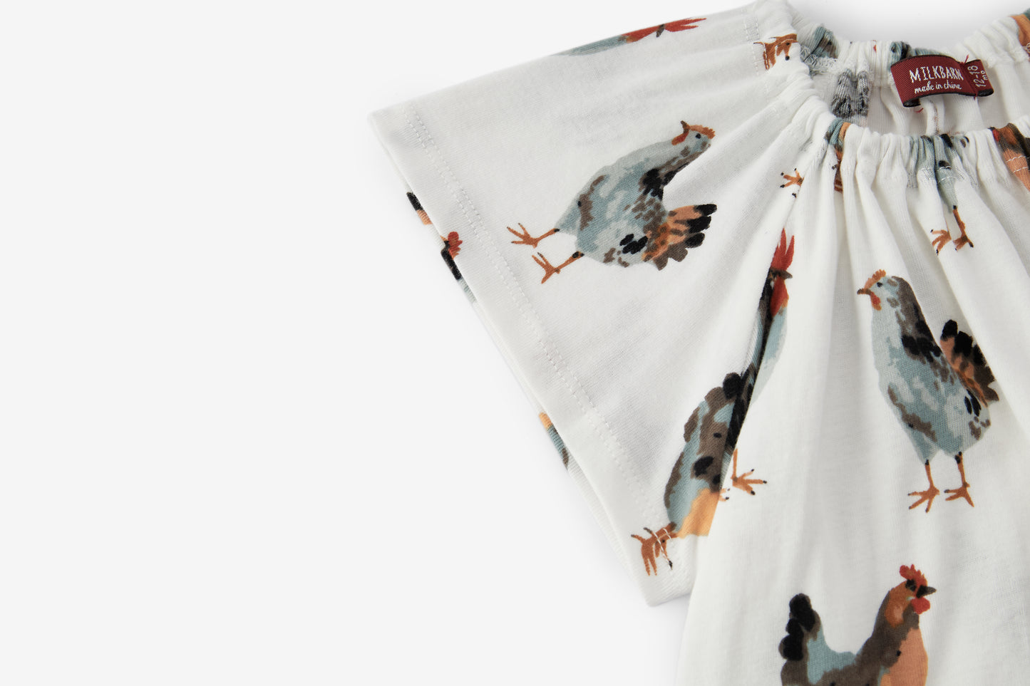 Closeup of sleeve and neckline on Milkbarn Chicken Organic Cotton Dress and Bloomer Set, showcasing soft organic cotton fabric and chicken pattern