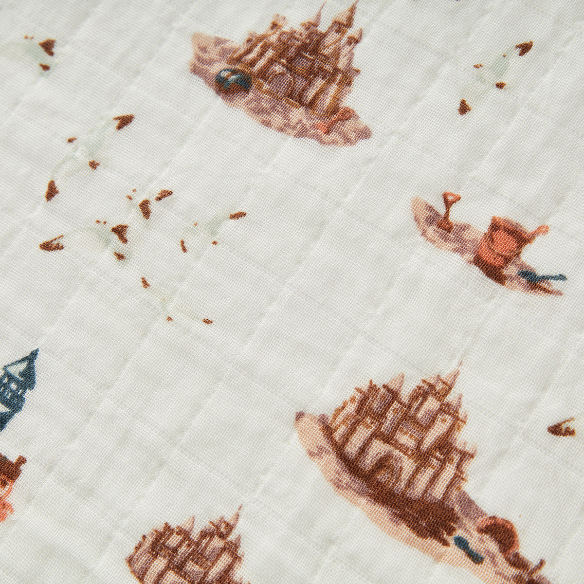 Closeup of Milkbarn Sandcastle Organic Cotton Muslin Burp Cloths, showing soft breathable white organic cotton fabric with playful sandcastle, lighthouse, and seagull print