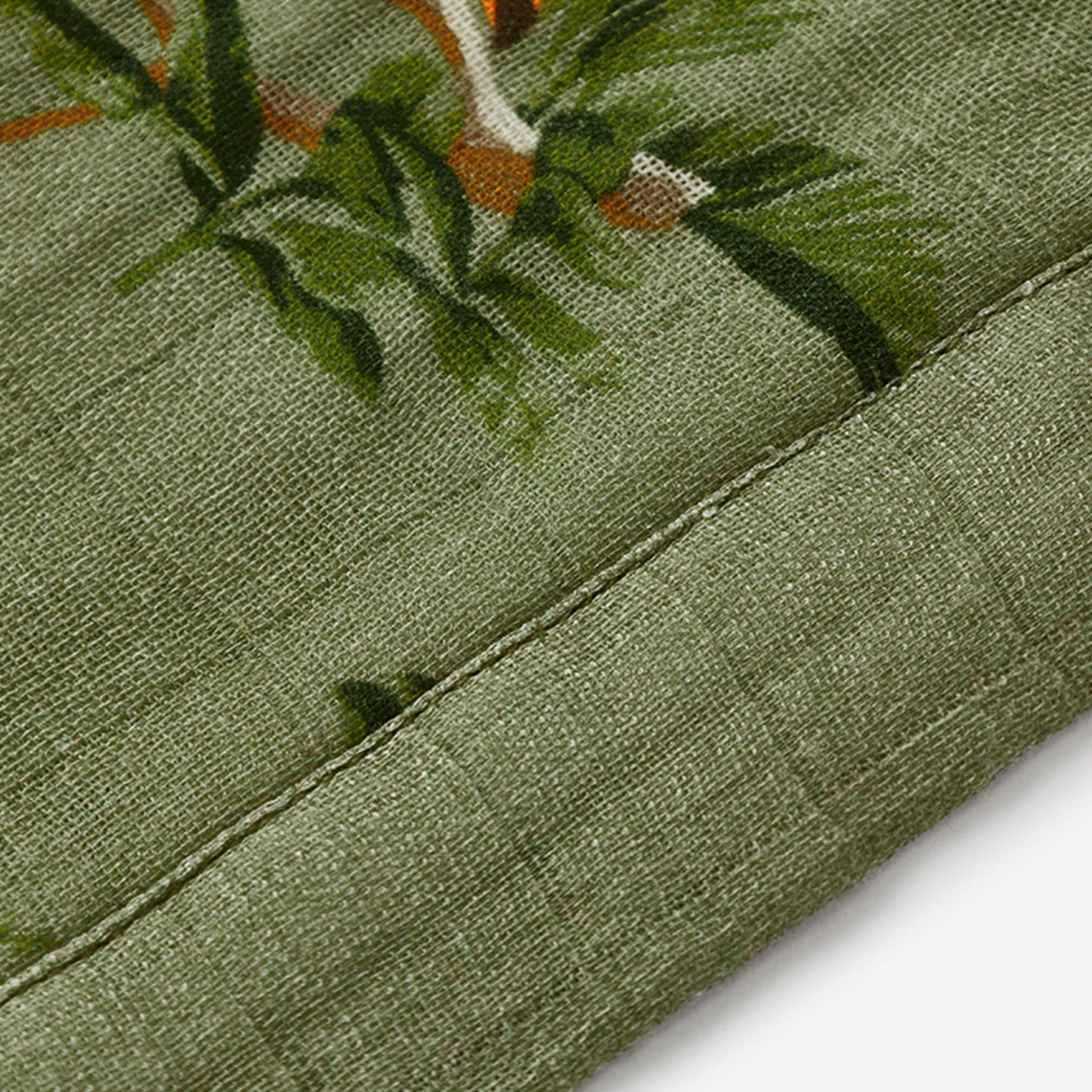 Closeup of Toucan Bamboo Mini Lovey muslin fabric and dark green trim for boys and girls