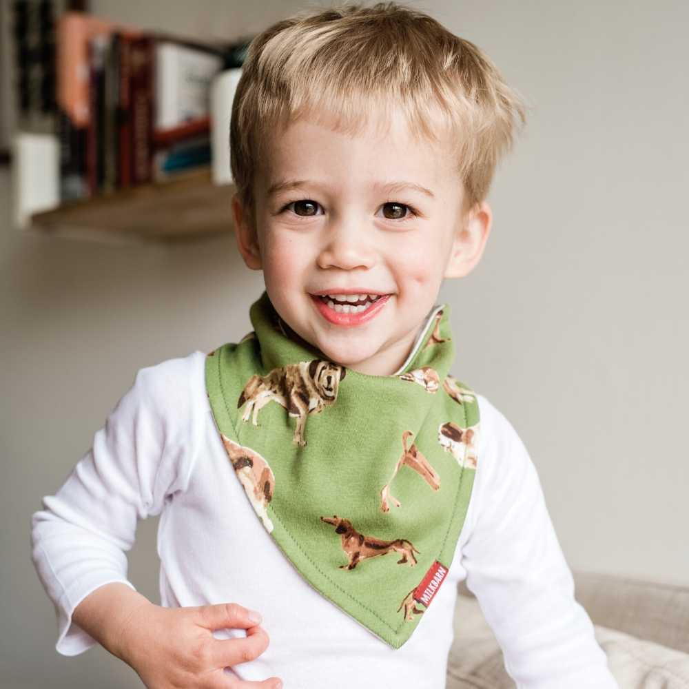 Little boy wearing Milkbarn Kerchief Bib in Green Dog print made from 100% GOTS certified organic cotton.