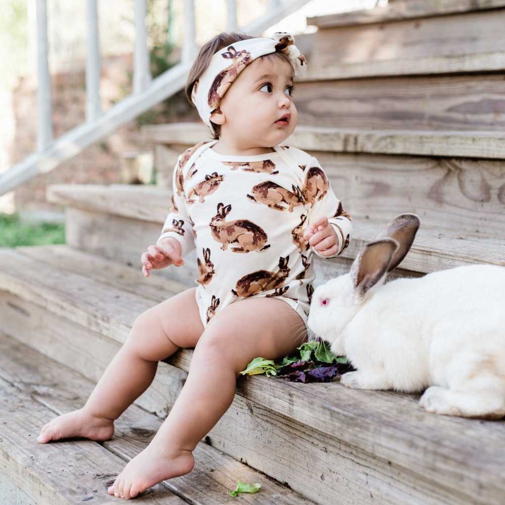 Little Baby Girl and Bunny on Wooden Steps Wearing the Long Sleeve One Piece and Headband in the Bunny Print by Milkbarn Kids