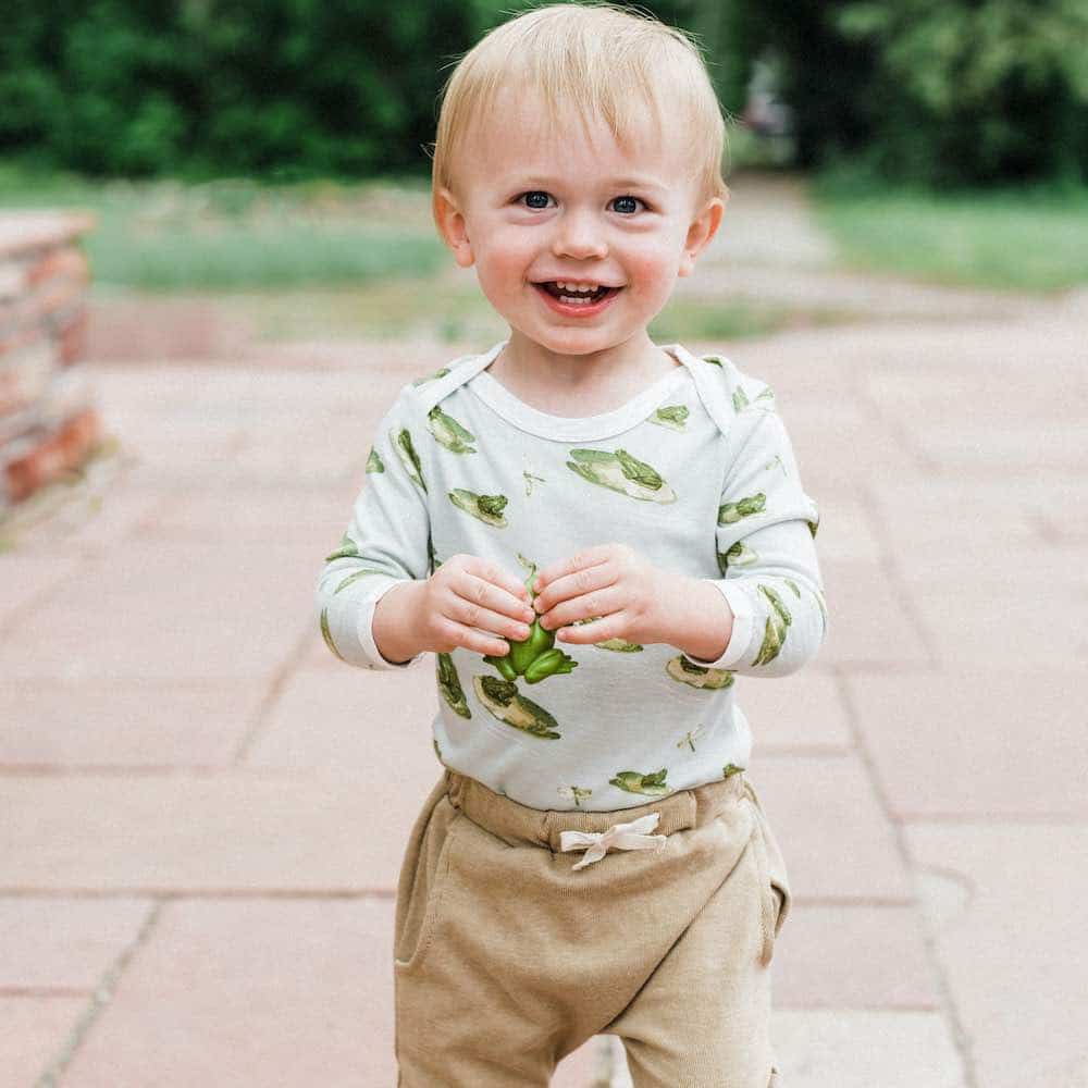 Little Baby Boy on a Patio Wearing the Bamboo Long Sleeve One Piece or Onesie in the Leapfrog Print and the Jogger Pant in the Rust Pinstripe by Milkbarn Kids