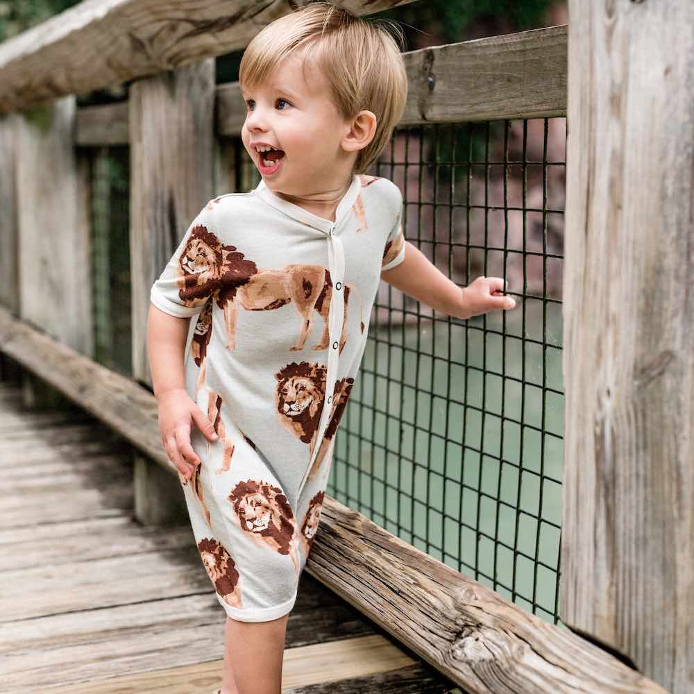 Baby boy on a bridge wearing Milkbarn Kids Bamboo Shortall in the Lion print