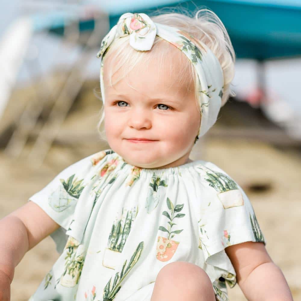 Little baby girl on the beach wearing Milkbarn Kids Bamboo knotted Headband in the Potted Plants Print