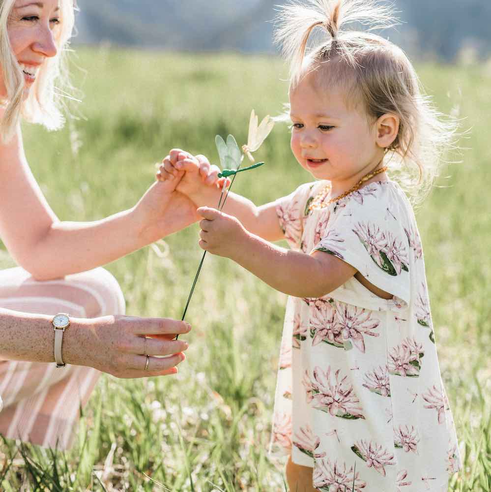 Mom and Little Baby Girl in a Field Wearing the Bamboo Dress and Bloomer Set in the Water Lily Print by Milkbarn Kids