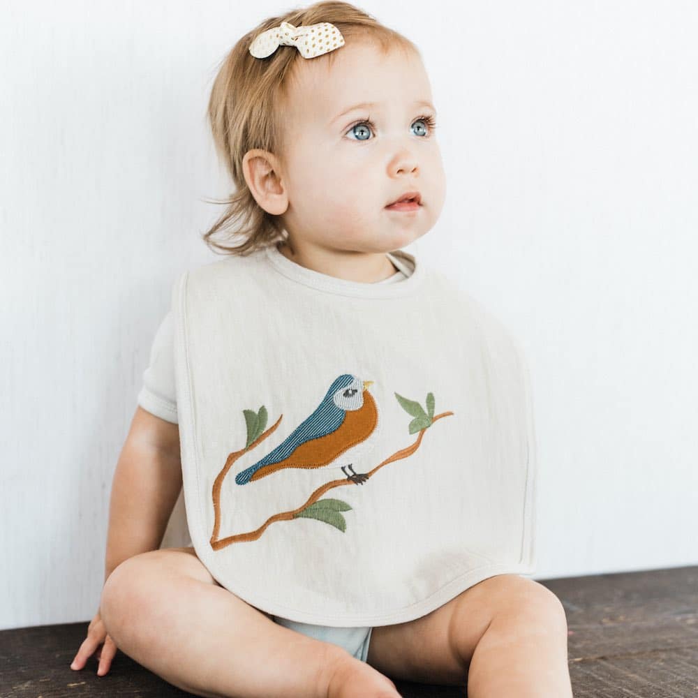 Little girl wearing Milkbarn Applique Linen Bib with Bird applique