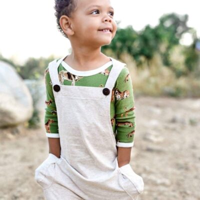 Baby Boy in a Field Wearing Organic Cotton Heathered Overalls by Milkbarn Kids