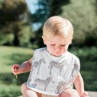 Little Boy in the Park Wearing the Organic Cotton Traditional Bib in the Grey Zebra Print by Milkbarn Kids