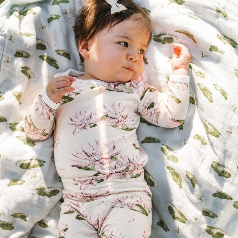 Little Girl on a Leapfrog Big Lovey Blanket Wearing a Bamboo Long Sleeve One Piece and Leggings in the Water Lily Print by Milkbarn Kids