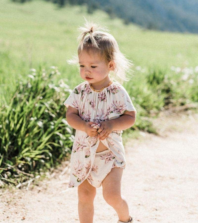 Wholesale SaleLittle Baby Girl on a Dirt Path Wearing the Bamboo Dress and Bloomers in the Water Lily Print by Milkbarn Kids