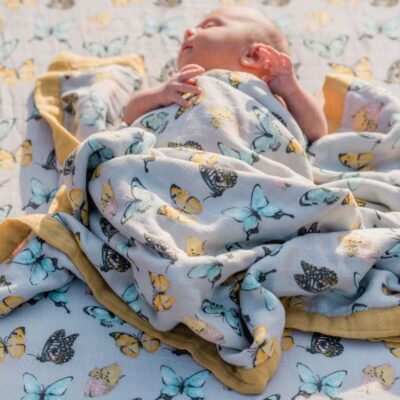 Baby Laying on Muslin Fitted Crib Sheets by Milkbarn Kids in the Butterfly Print