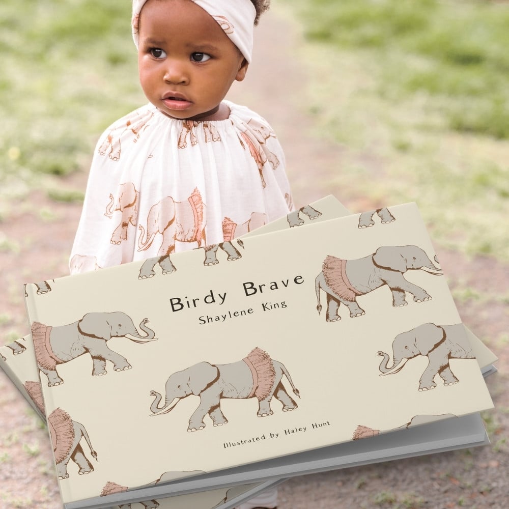 Little girl outside wearing the Tutu Elephant Bamboo Dress and Leggings with a matching headband. The print matches the children's book illustrations in Birdy Brave by Shaylene King for Milkbarn Kids
