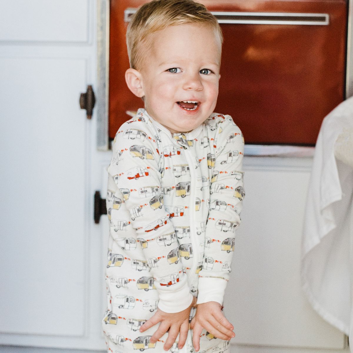 Baby Boy in a vintage trailer wearing the organic zipper pajamas with the vintage trailers print by Milkbarn Kids
