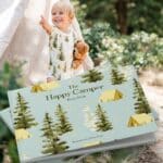 Photo of cover artwork of The Happy Camper by Rory Feek with Lifestyle image of baby boy wearing a bamboo one piece in the camping print by Milkbarn Kids