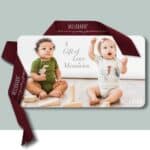 A Milkbarn Kids E-Gift Card of Love wrapped in ribbon with two babies wearing applique one pieces on the Milkbarn gift card