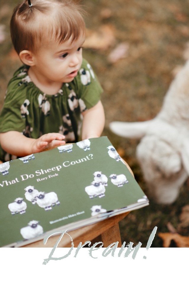 A sheep and a Baby girl holding the book, What do Sheep Count by Rory Feek with Illustrations by Haley Hunt for Milkbarn