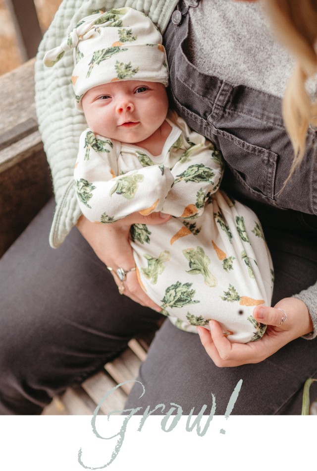Mom holding a baby in her arms wearing the organic cotton gown and hat set in the Fresh Veggies print by Milkbarn
