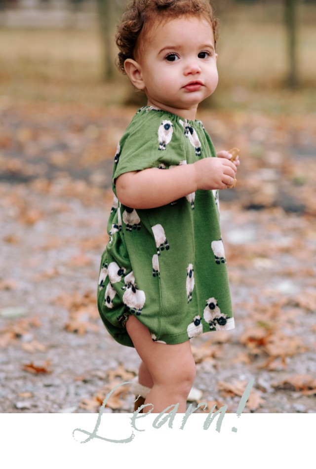 Baby girl outside wearing the bamboo dress and bloomer set in the Valais sheep print by Milkbarn