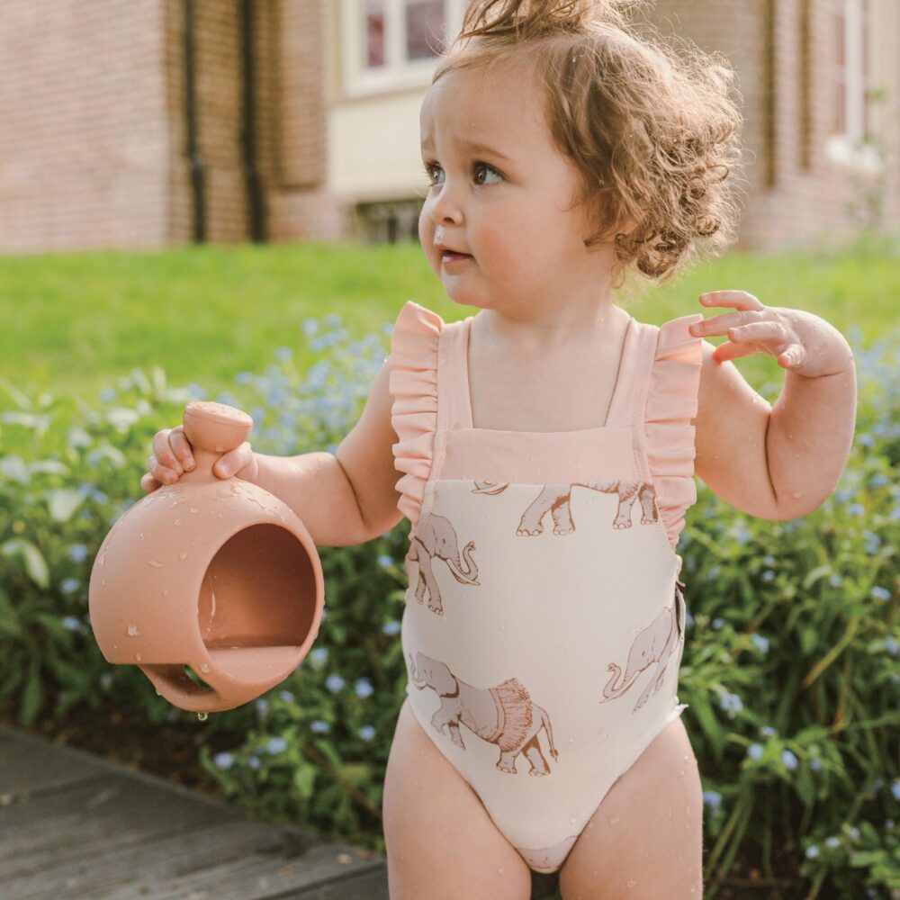 Baby girl outside near the pool wearing the Tutu Elephant Ruffle Square Neck One Piece Swimsuit by Milkbarn