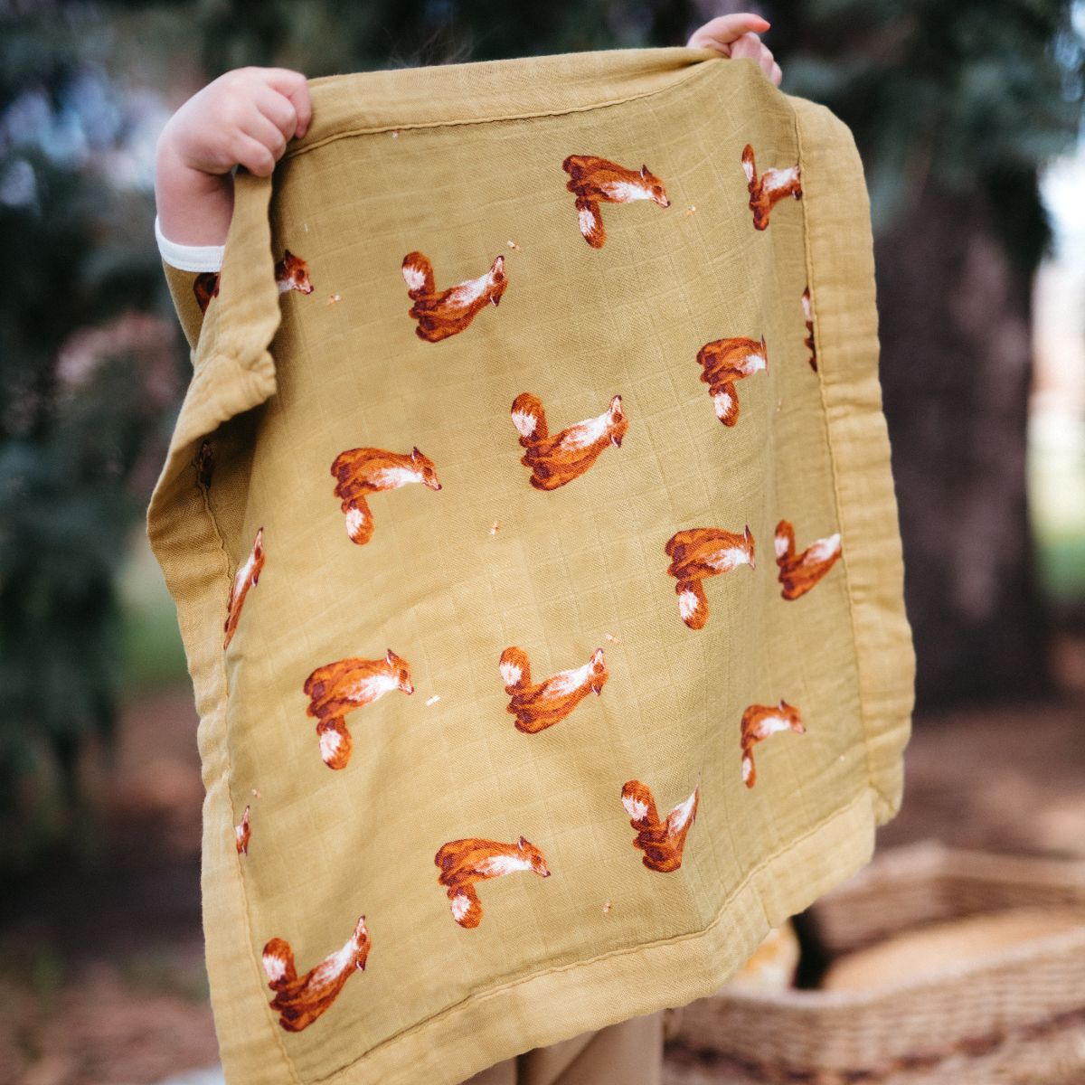 A child in the forest holds up the Gold Fox Mini Lovey security blanket