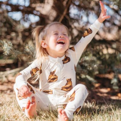 Baby girl in a park holding pinecones wearing the bamboo Honey Bear Zipper Pajama