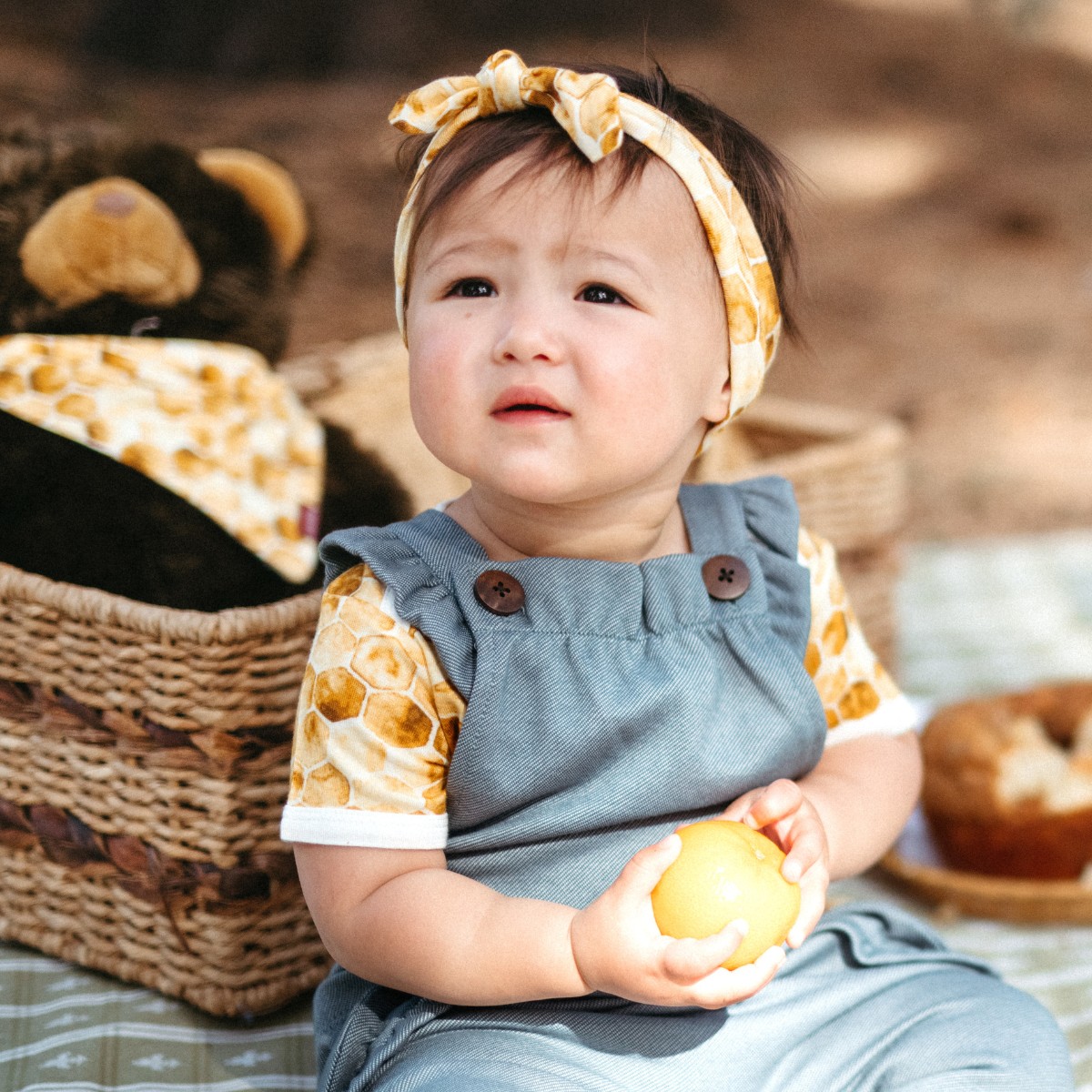 Baby girl outside having a picnic wearing the Honeycomb Bamboo Knotted Headband by Milkbarn