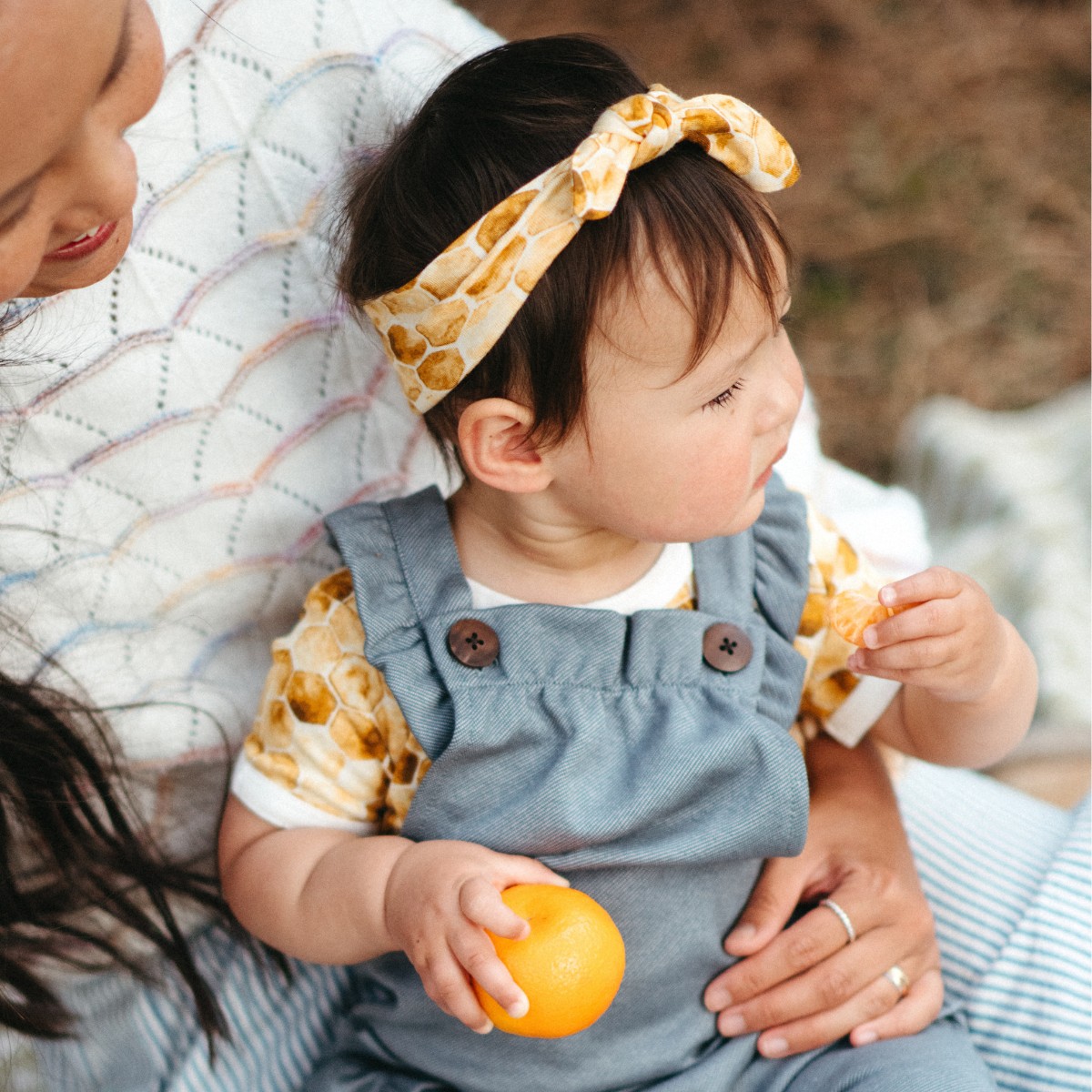 Baby girl outside having a picnic wearing the Honeycomb Bamboo Knotted Headband by Milkbarn